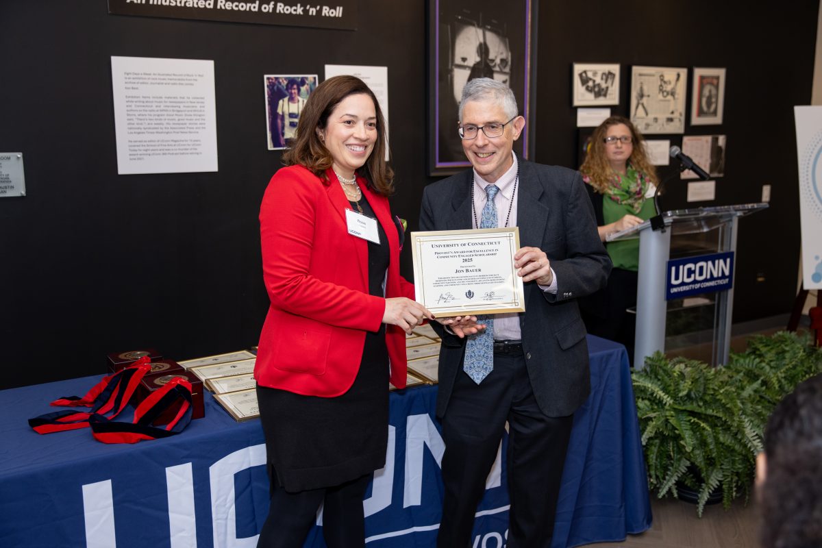 A group of people posing in front of a UConn sign.