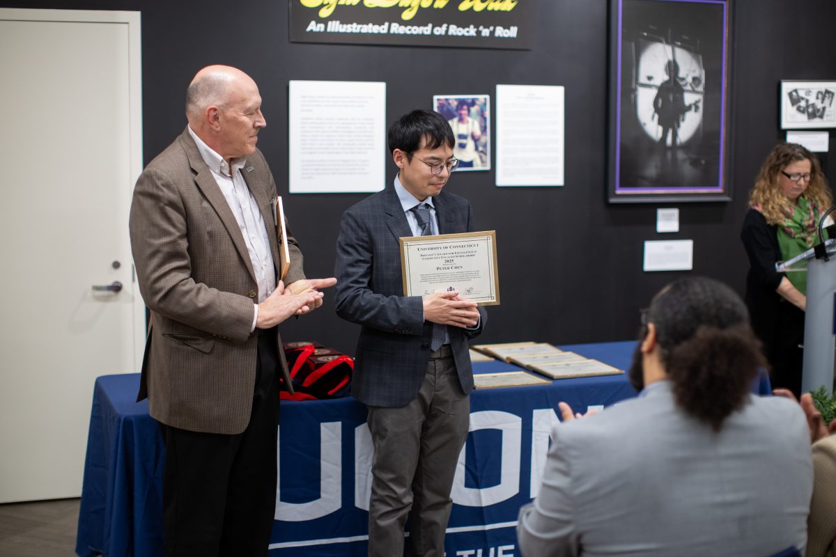 A group of people posing in front of a UConn sign.