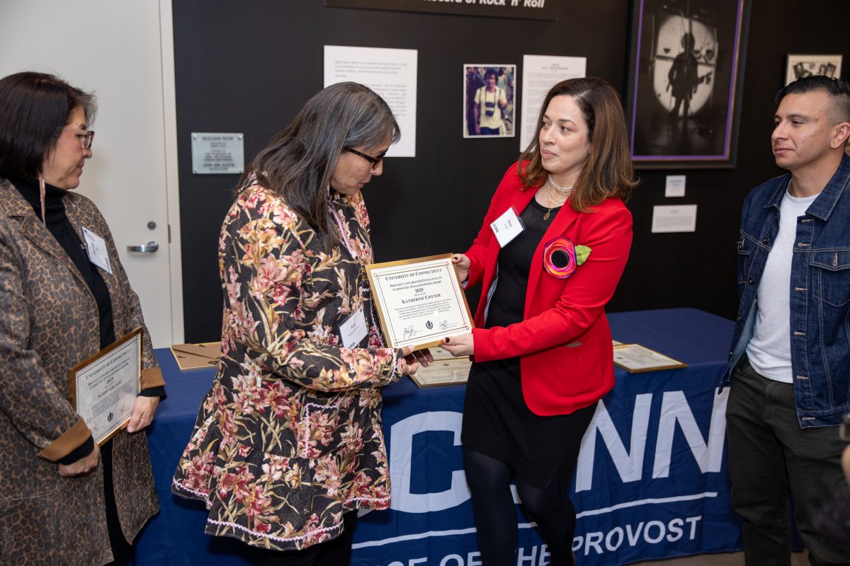 A group of people posing in front of a UConn sign.