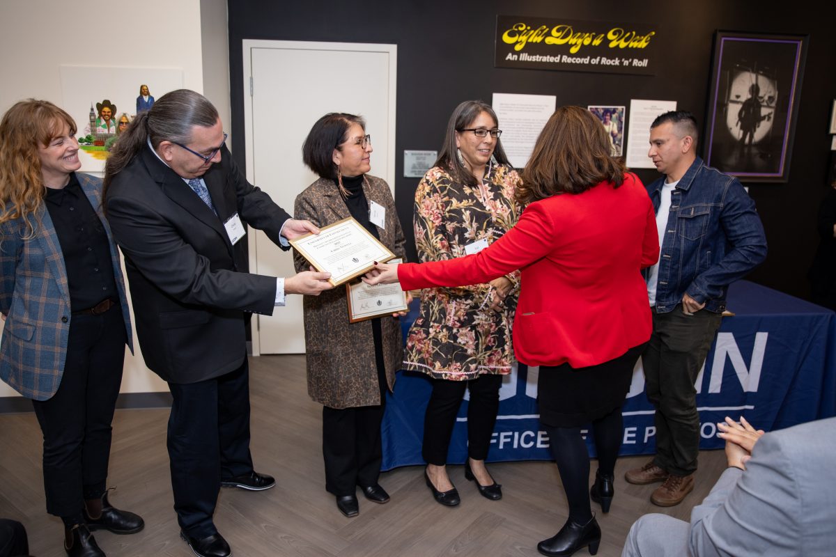 A group of people posing in front of a UConn sign.