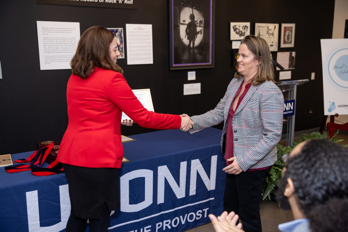 A group of people posing in front of a UConn sign.