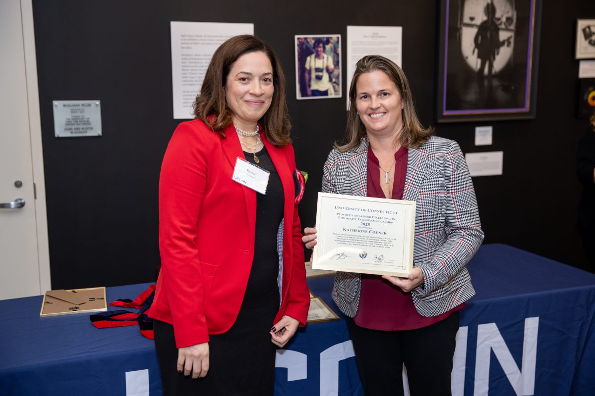 A group of people posing in front of a UConn sign.