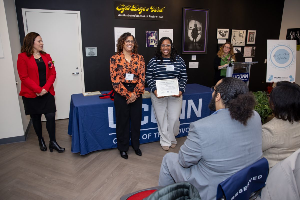 A group of people posing in front of a UConn sign.
