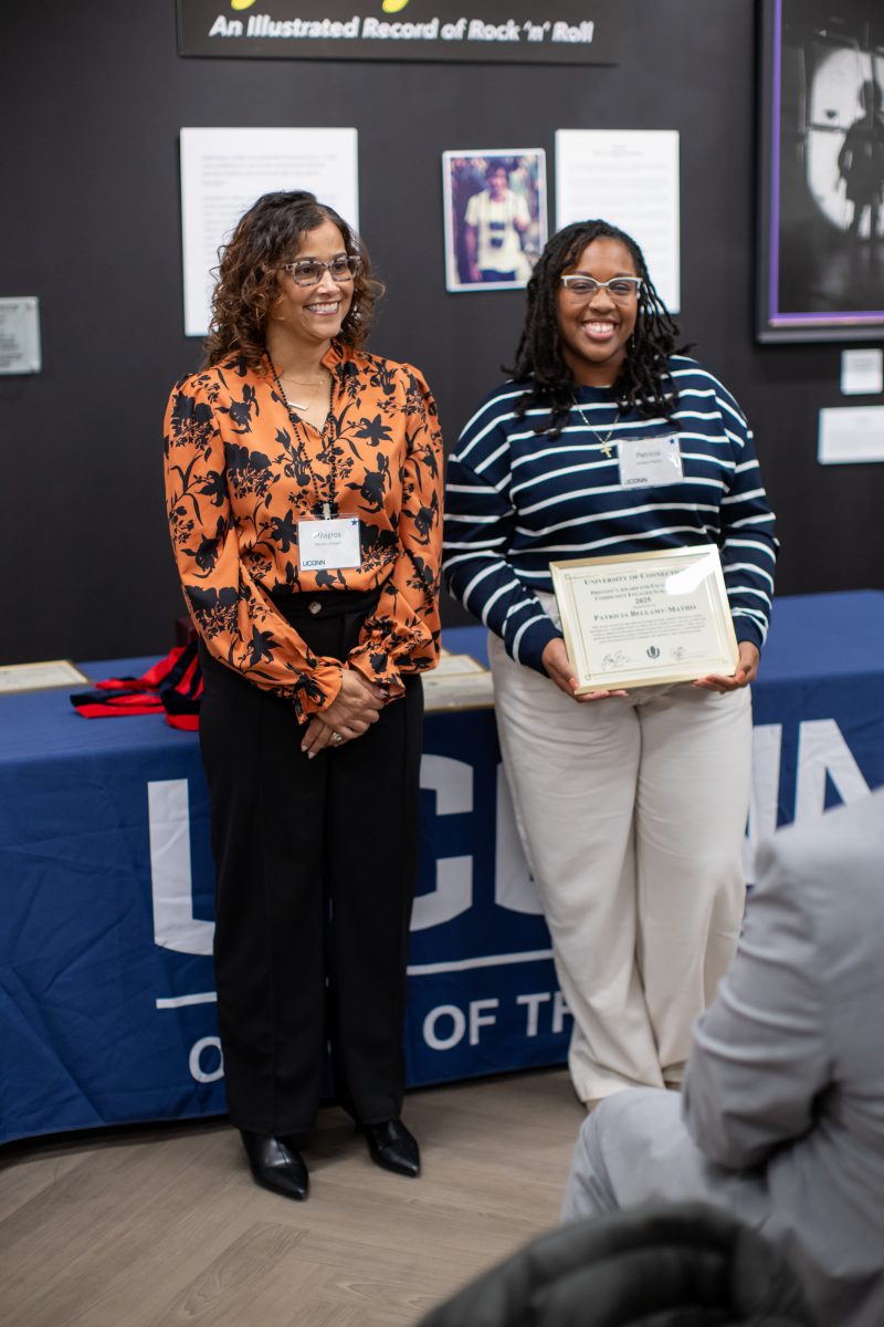 A group of people posing in front of a UConn sign.