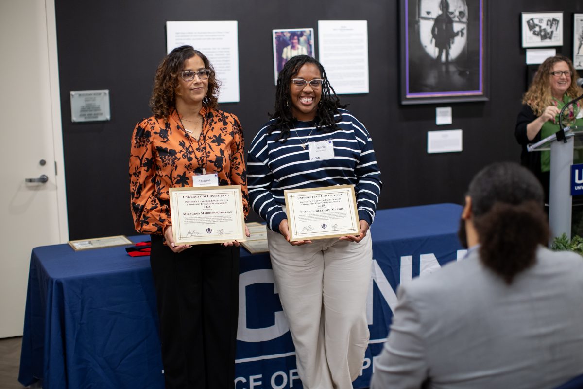A group of people posing in front of a UConn sign.