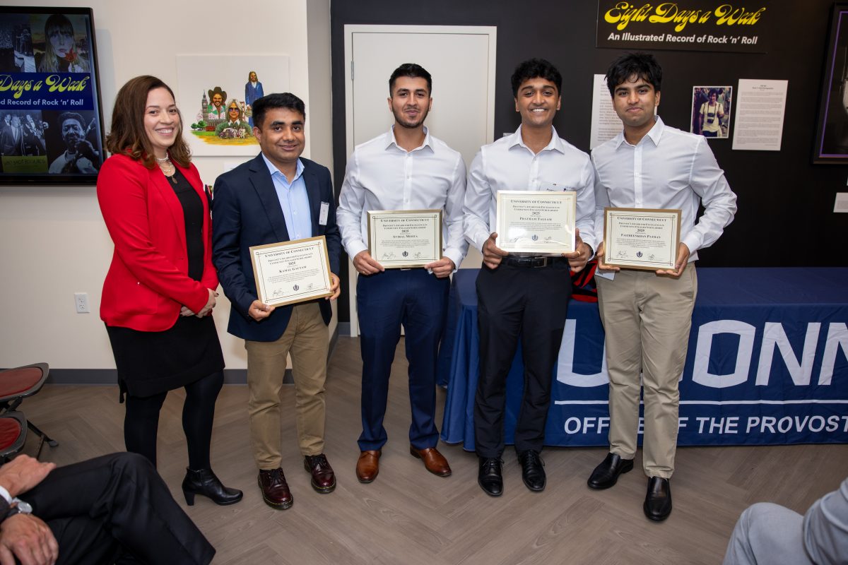 A group of people posing in front of a UConn sign.
