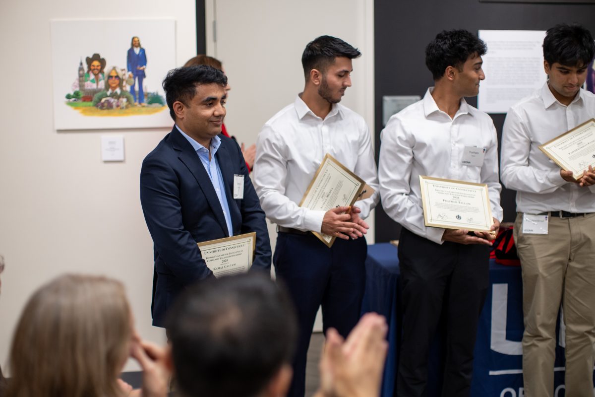 A group of people posing in front of a UConn sign.
