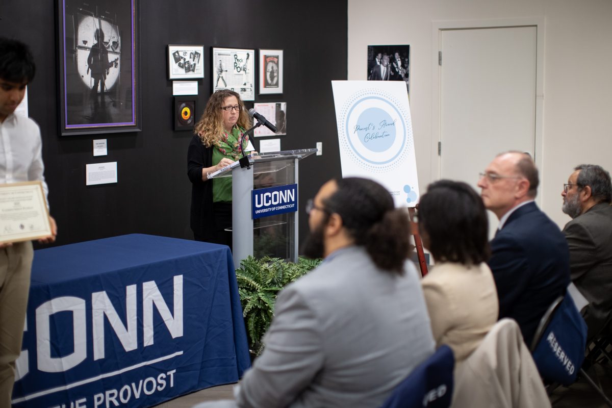 A group of people posing in front of a UConn sign.