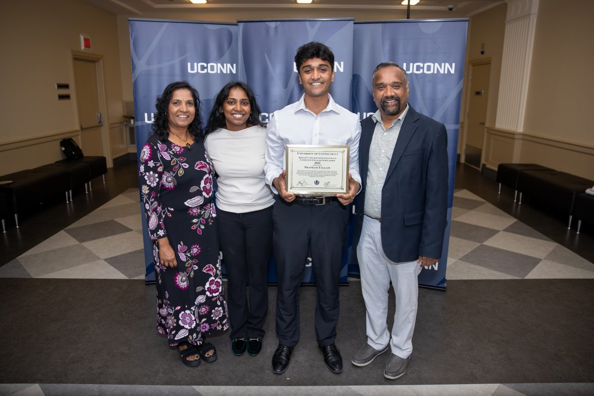 A group of people posing in front of a UConn sign.