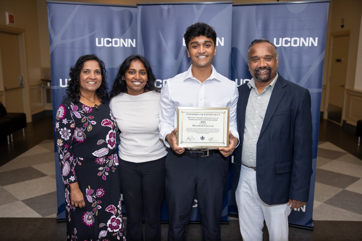 A group of people posing in front of a UConn sign.