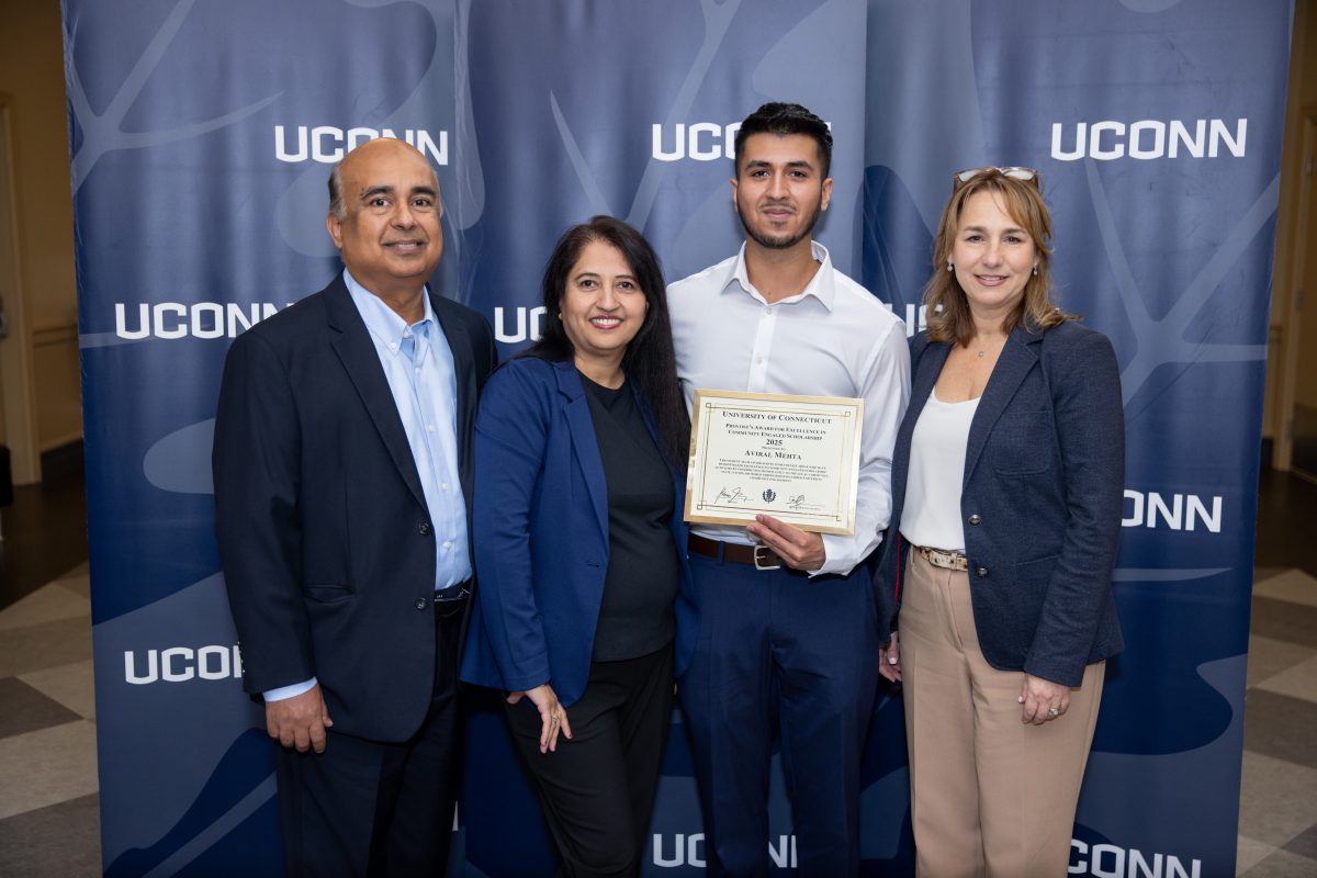 A group of people posing in front of a UConn sign.