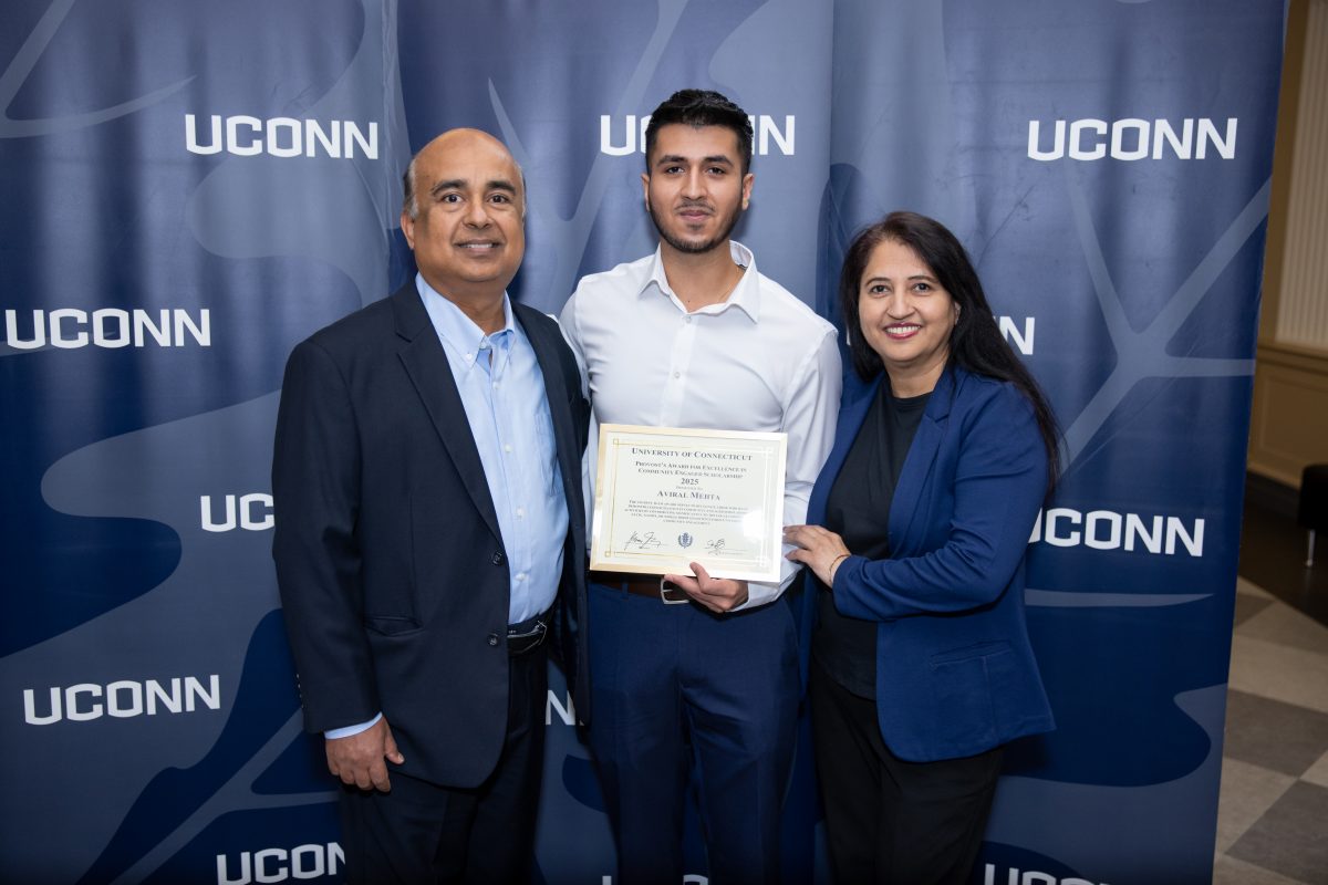 A group of people posing in front of a UConn sign.
