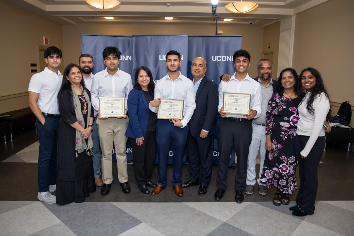 A group of people posing in front of a UConn sign.